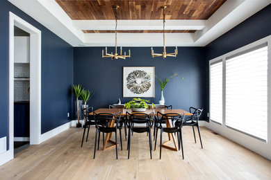 Imagen de comedor actual cerrado con paredes azules, suelo de madera clara y suelo beige