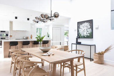 Idée de décoration pour une salle à manger ouverte sur le salon design avec un mur blanc, parquet clair et un sol beige.