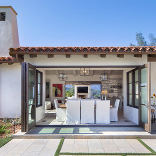 Example of a mid-sized tuscan beige floor and light wood floor great room design in Santa Barbara with white walls and no fireplace