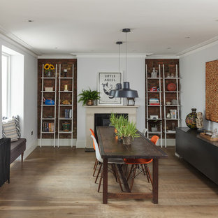 Photo of a medium sized bohemian dining room in London with grey walls, medium hardwood flooring, brown floors and a standard fireplace.