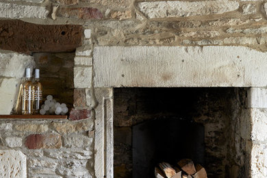 Geschlossenes, Mittelgroßes Landhaus Esszimmer mit grauer Wandfarbe, Teppichboden, Kaminofen, Kaminumrandung aus Stein und beigem Boden in Gloucestershire