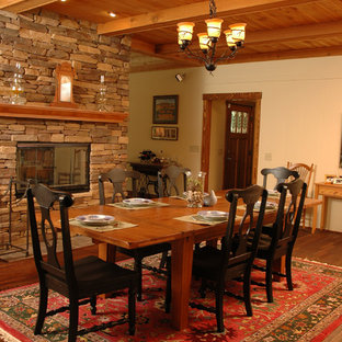 Modelo de comedor de estilo americano, de tamaño medio, abierto, con paredes beige, suelo de madera en tonos medios, chimenea de doble cara y marco de chimenea de piedra