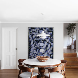 Inspiration for a mid-sized transitional kitchen/dining combo in Sydney with grey walls, medium hardwood floors and brown floor.