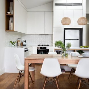 Photo of a mid-sized contemporary kitchen/dining combo in Sydney with white walls, medium hardwood floors and brown floor.