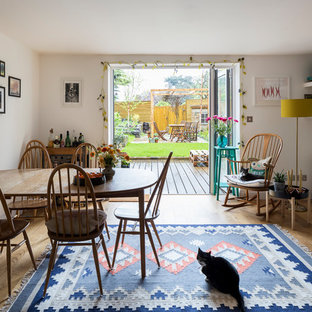 This is an example of a small scandi dining room in London with white walls, light hardwood flooring, a standard fireplace and brown floors.