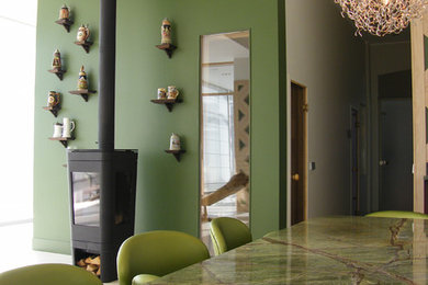 Cette image montre une salle à manger design de taille moyenne avec un mur vert et un poêle à bois.
