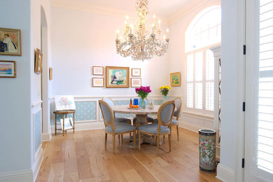 Cette image montre une grande salle à manger traditionnelle avec un mur blanc, un sol en bois brun et un sol marron.