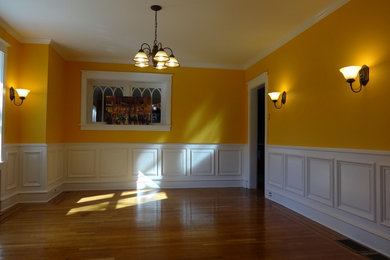 Imagen de comedor clásico grande cerrado con parades naranjas, suelo de madera en tonos medios y suelo marrón