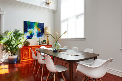 Exemple d'une salle à manger ouverte sur le salon tendance de taille moyenne avec un mur blanc, un sol en bois brun, aucune cheminée et un sol marron.