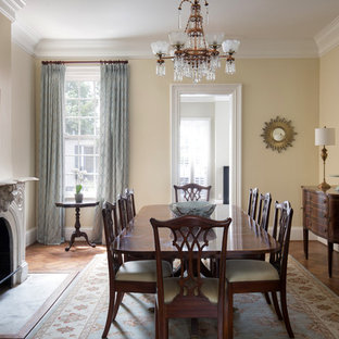 Foto di una sala da pranzo vittoriana chiusa con pareti beige, parquet scuro, camino classico, cornice del camino in cemento e pavimento marrone
