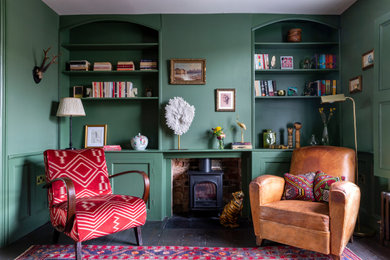 ロンドンにある高級な中くらいなエクレクティックスタイルのおしゃれなダイニングキッチン (緑の壁、濃色無垢フローリング、薪ストーブ、レンガの暖炉まわり、茶色い床) の写真