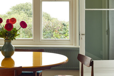 Geschlossenes, Mittelgroßes Stilmix Esszimmer mit grüner Wandfarbe, dunklem Holzboden, Kamin und Kaminumrandung aus Stein in Surrey