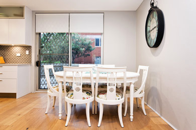 Imagen de comedor de cocina minimalista pequeño con paredes grises y suelo de madera clara
