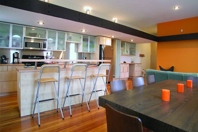 Moderne Wohnküche mit oranger Wandfarbe und braunem Holzboden in Omaha