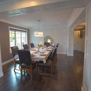 Diseño de comedor de estilo americano, grande, abierto, con paredes grises, suelo de madera oscura, chimenea de doble cara, marco de chimenea de piedra y suelo marrón