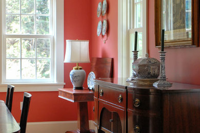 Modelo de comedor clásico de tamaño medio cerrado sin chimenea con paredes rojas y suelo de madera clara