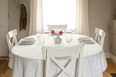 Aménagement d'une salle à manger ouverte sur le salon de taille moyenne avec un mur gris, parquet clair, un manteau de cheminée en bois et une cheminée standard.