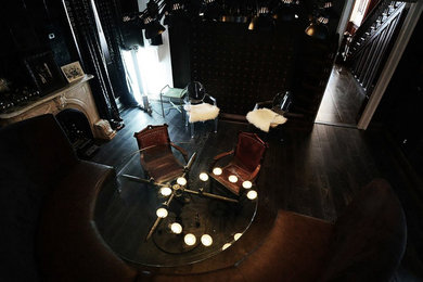 Idées déco pour une salle à manger ouverte sur la cuisine éclectique de taille moyenne avec un mur noir, parquet foncé, un poêle à bois, un manteau de cheminée en pierre et un sol noir.