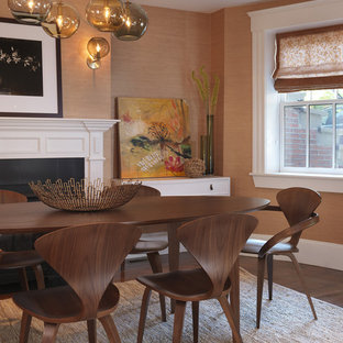 Immagine di una sala da pranzo tradizionale con pareti arancioni, parquet scuro, camino classico e cornice del camino in legno