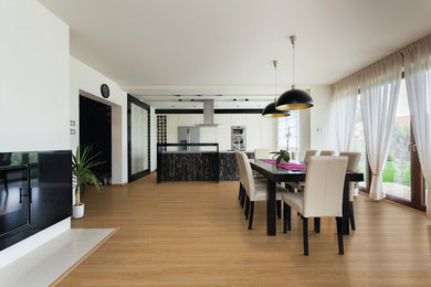 Example of a mid-sized minimalist medium tone wood floor kitchen/dining room combo design in Other with white walls and no fireplace