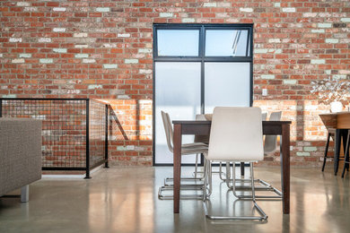 Immagine di una sala da pranzo aperta verso il soggiorno industriale di medie dimensioni con pavimento in cemento