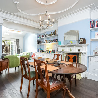 Inspiration for a medium sized traditional dining room in London with dark hardwood flooring, a standard fireplace, brown floors and blue walls.