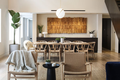 Immagine di una sala da pranzo aperta verso la cucina minimal di medie dimensioni con pareti bianche, parquet chiaro e nessun camino
