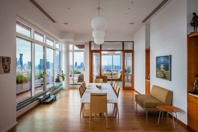 Large contemporary enclosed dining room in New York with white walls, light hardwood flooring and no fireplace.