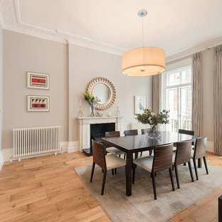 Inspiration for a classic dining room in London with grey walls, light hardwood flooring, a standard fireplace and beige floors.
