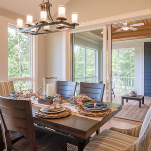 Diseño de comedor de estilo americano, de tamaño medio, abierto, con paredes grises, suelo de madera en tonos medios, chimenea de doble cara, marco de chimenea de piedra y suelo marrón