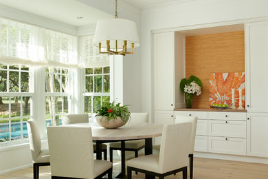 This is an example of a medium sized world-inspired dining room in Miami with white walls and light hardwood flooring.