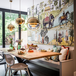 Idées déco pour une salle à manger ouverte sur la cuisine éclectique avec un mur multicolore, aucune cheminée et un sol gris.