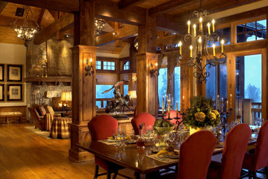 Photo of a rustic open plan dining room in Denver with medium hardwood flooring and a stone fireplace surround.