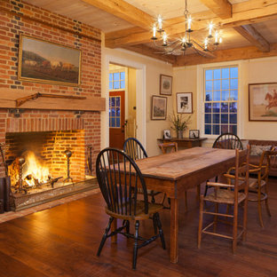 Esempio di una grande sala da pranzo aperta verso il soggiorno country con parquet scuro, camino classico, cornice del camino in mattoni e pareti gialle
