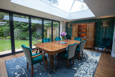 Large bohemian open plan dining room in Berkshire with green walls.