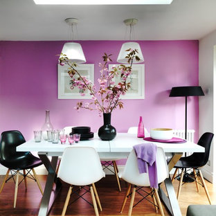 Réalisation d'une salle à manger design avec un mur rose et un sol en bois brun.