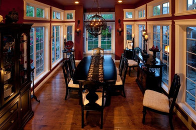 Example of a large classic medium tone wood floor and brown floor enclosed dining room design in Vancouver with red walls and no fireplace