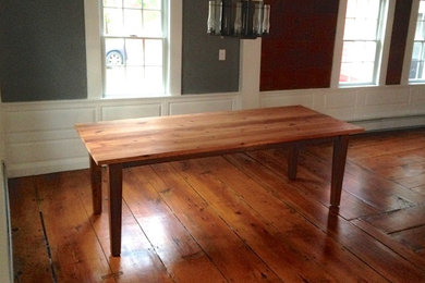 Modelo de comedor campestre grande con paredes rojas y suelo de madera en tonos medios