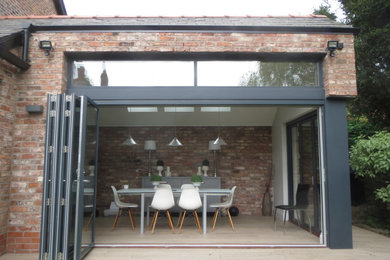 Medium sized contemporary kitchen/dining room in Cheshire with white walls, ceramic flooring, no fireplace, beige floors, a vaulted ceiling and brick walls.