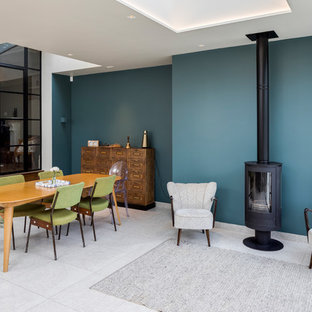 Inspiration for a contemporary open plan dining room in London with blue walls, a wood burning stove, a metal fireplace surround and grey floors.