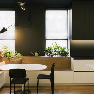 Cette photo montre une grand salle à manger ouverte sur la cuisine tendance avec un mur noir, un sol en bois brun et aucune cheminée.