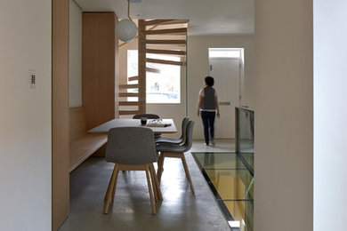 Cette image montre une petite salle à manger ouverte sur le salon design avec un mur blanc et sol en béton ciré.
