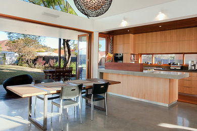 Contemporary kitchen/dining room in Sydney with white walls and concrete flooring.