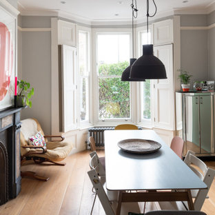 Design ideas for a medium sized scandi open plan dining room in London with grey walls, light hardwood flooring, a standard fireplace, a stone fireplace surround and brown floors.
