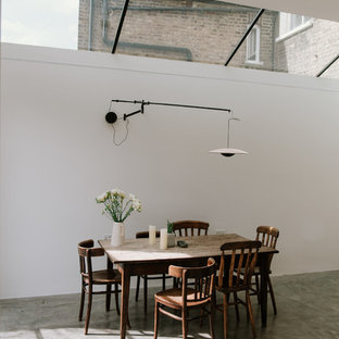 Medium sized industrial dining room in London with white walls, concrete flooring and grey floors.