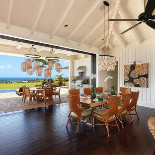 Immagine di una sala da pranzo aperta verso il soggiorno stile marino di medie dimensioni con pareti bianche, pavimento in bambù, pavimento nero e nessun camino