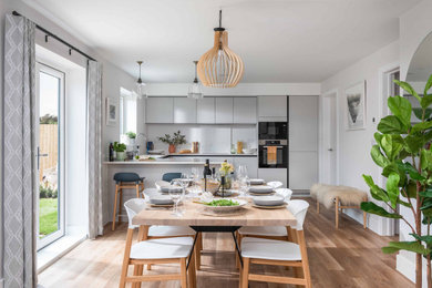 Immagine di una sala da pranzo aperta verso la cucina minimal con pareti bianche, pavimento in legno massello medio, nessun camino e pavimento marrone