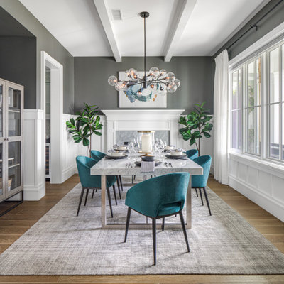 Large transitional light wood floor, brown floor, exposed beam and wainscoting enclosed dining room photo in Orange County with gray walls, a standard fireplace and a wood fireplace surround