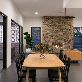 Contemporary open plan dining in Brisbane with white walls, a ribbon fireplace, a stone fireplace surround and grey floor.