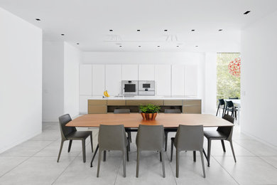 Foto di una grande sala da pranzo aperta verso la cucina minimal con pareti bianche, pavimento con piastrelle in ceramica e pavimento grigio